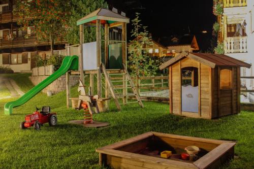 a playground with a sandbox and a play set at Hotel Alpi in Campitello di Fassa