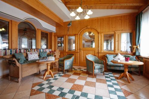 a library with chairs and a couch and tables at Hotel Alpi in Campitello di Fassa