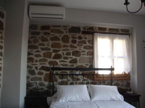 VolissosにあるVolissos Homesの石壁のベッドルーム(ベッド1台、窓付)