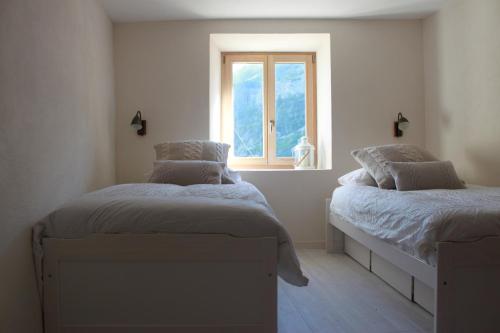 2 Betten in einem Zimmer mit Fenster in der Unterkunft L'Eyssart in Les Vigneaux