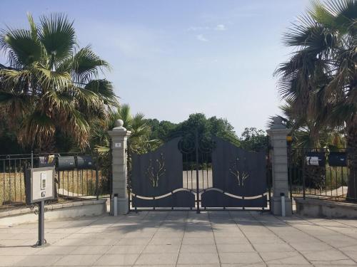 a black gate with palm trees in the background at Folco Studio Apartment in Piazza Armerina
