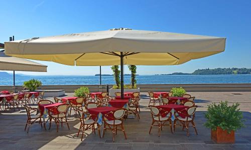 a group of tables and chairs under a large umbrella at Hotel Du Lac Gardone Riviera in Gardone Riviera