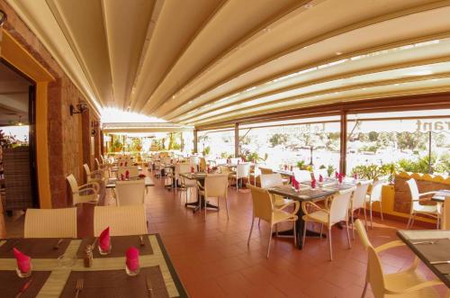 un comedor con mesas, sillas y ventanas en Hôtel Le Romantique en Porto Ota