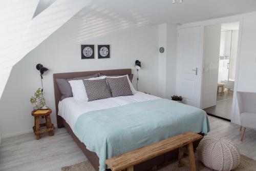 een witte slaapkamer met een groot bed en een houten bank bij Studio De Bilt in De Bilt