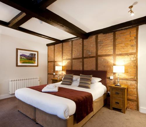 a bedroom with a large bed and a wooden wall at The Talbot Hotel in Ledbury
