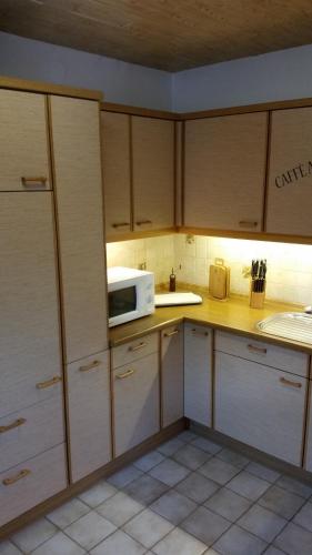 eine Küche mit Holzschränken und einer Mikrowelle in der Unterkunft Ferienwohnung-Bullendorf in Bullendorf
