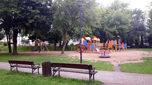 オストルダにあるApartament Parkowyのベンチ2台と遊び場付きの公園