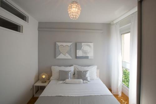 a white bedroom with a bed and a chandelier at Apartment Lana in Split
