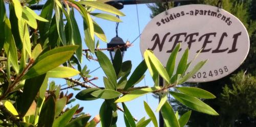 a sign for a meezed restaurant hanging from a tree at Nefeli Studios in Loutra Edipsou
