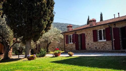 an old stone house with red shutters in a yard at Agriturismo Podere Valdo in Gavorrano