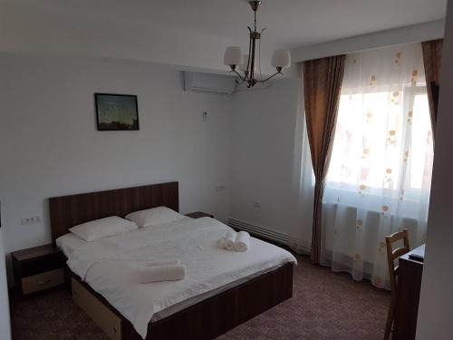 a bedroom with a bed with white sheets and a window at SkyRoomsHorezu in Horezu