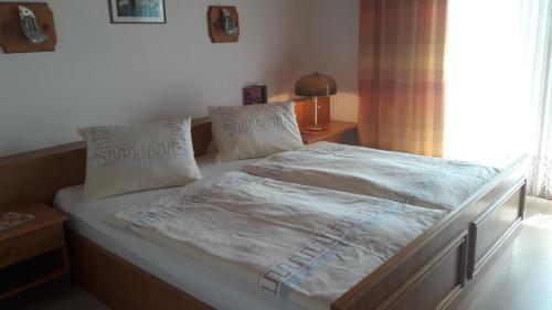 a bed with white sheets and pillows in a bedroom at Ferienwohnung Gästehaus Inge in Zlan