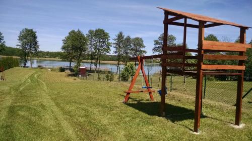 a swing set in the grass next to a lake at Domek Letniskowy Krejwince in Krejwińce
