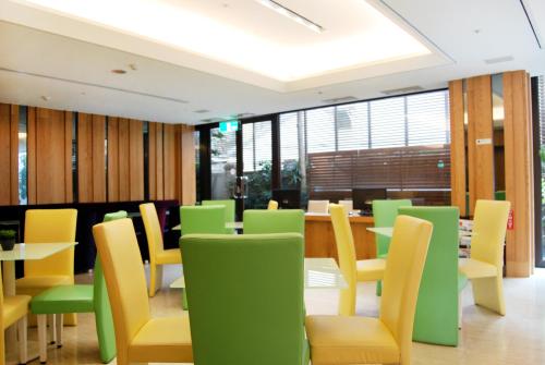 a dining room with green and yellow chairs and tables at Century Hotel Taoyuan in Taoyuan
