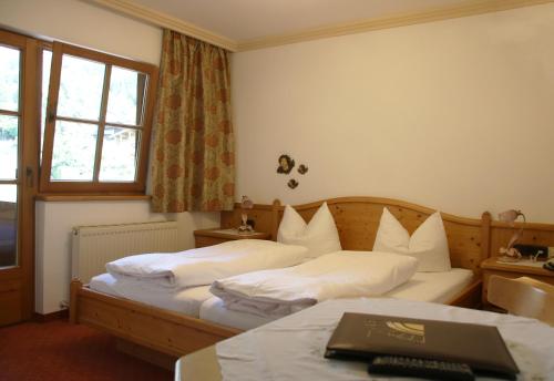 a hotel room with two beds and a window at Pension Sonnhof in Brixen im Thale