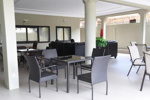 ein Esszimmer mit Tischen und Stühlen und einer Couch in der Unterkunft Hôtel Mirambeau in Lomé