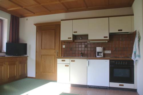 an empty kitchen with white appliances and a television at Apartment Sonnhof in Brixen im Thale