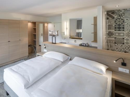 1 Schlafzimmer mit 2 weißen Betten und einem Waschbecken in der Unterkunft Hotel Matteo in Flachau