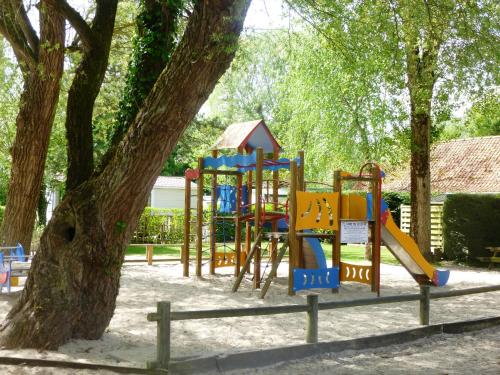 a playground in a park with a tree at Caravaning Les Tourterelles in Rang-du-Fliers