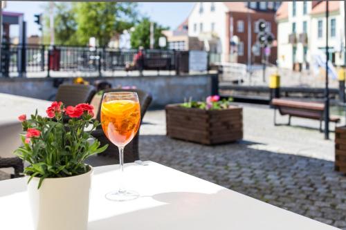 a glass of wine sitting on a table with flowers at Der Insulaner - Hotel & Restaurant in Malchow