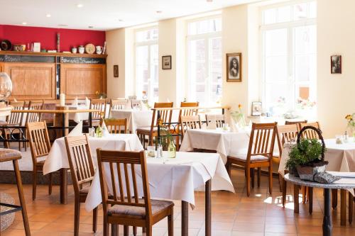 a restaurant with white tables and chairs and windows at Der Insulaner - Hotel & Restaurant in Malchow