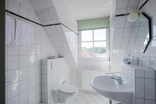 a white bathroom with a toilet and a sink at Der Insulaner - Hotel & Restaurant in Malchow