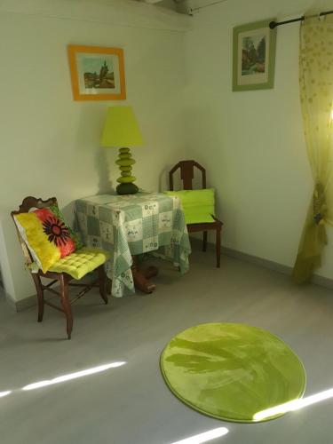 - un salon avec une table, des chaises et un tapis vert dans l'établissement Chambres d'hôtes Au Pére Louis, à Labastide-du-Vert