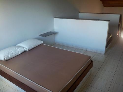 a bed in a room with a white wall at Chales Mar Azul in Caraguatatuba