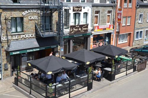 a group of people sitting outside a restaurant with umbrellas at Auberge Le Temps des Saveurs in Paliseul