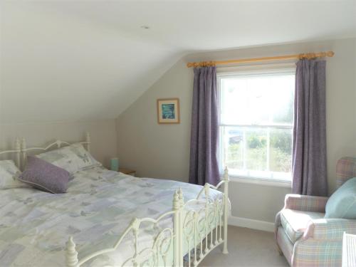 um quarto com uma cama branca e uma janela em Chalice Loft em Glastonbury