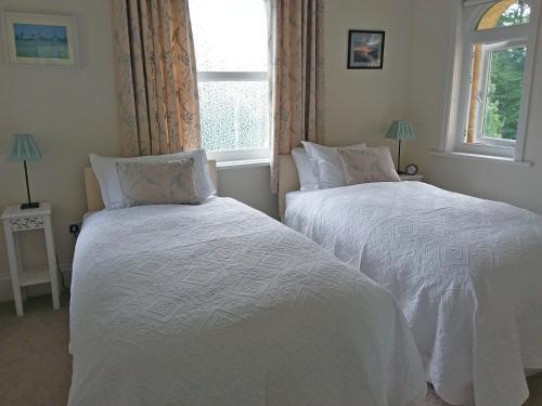 two white beds in a bedroom with a window at Chine Side in Shanklin