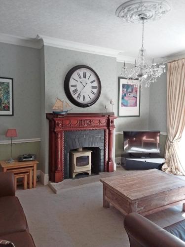 a living room with a fireplace with a clock on the wall at Chine Side in Shanklin