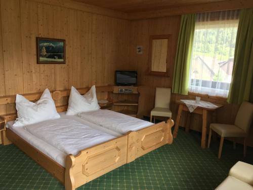 a bedroom with a bed with a television and a window at Gästehaus Lemmerer in Obersdorf