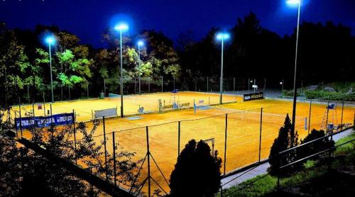 a tennis court lit up at night with lights at Apartments Zlatko in Ičići