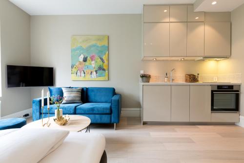 Il comprend un salon avec un canapé bleu et une cuisine. dans l'établissement 2 Døtre Apartments, à Bergen