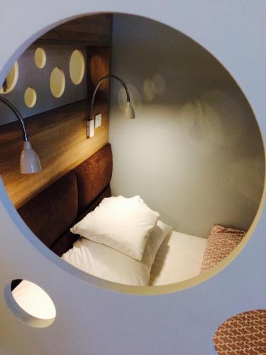a small room with a bed and a round mirror at Piper Cytadela Apartament in Poznań