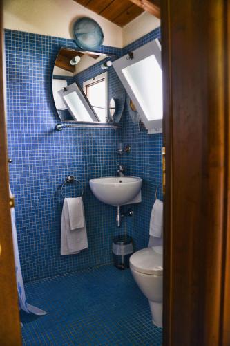 a blue tiled bathroom with a sink and a toilet at Los Flamingos in La Maddalena