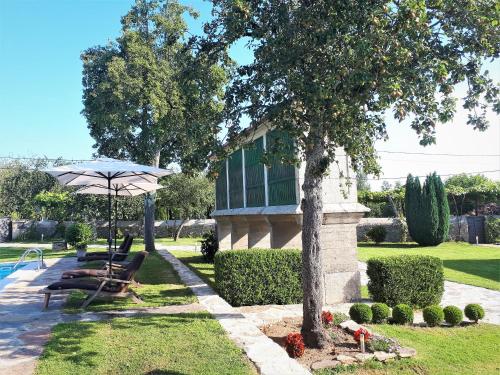 a house with a table and an umbrella next to a pool at Torres de Moreda in A Estrada