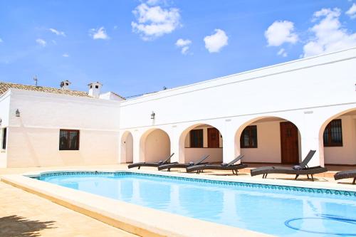 - une piscine dans une cour avec des chaises et un bâtiment dans l'établissement Casa Solariega, à Villena