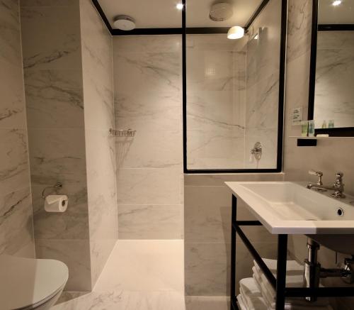 La salle de bains blanche est pourvue d'un lavabo et d'une douche. dans l'établissement Getaway Studios Brussels Airport, à Zaventem