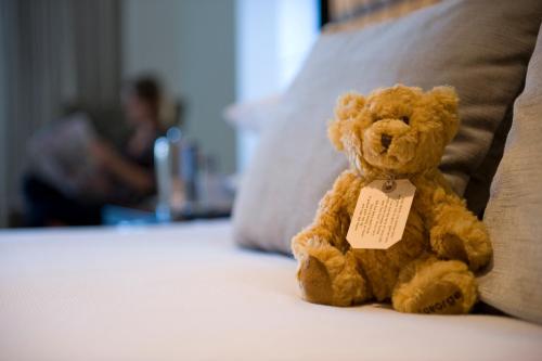 a teddy bear sitting on a bed with a tag on it at The George in Christchurch