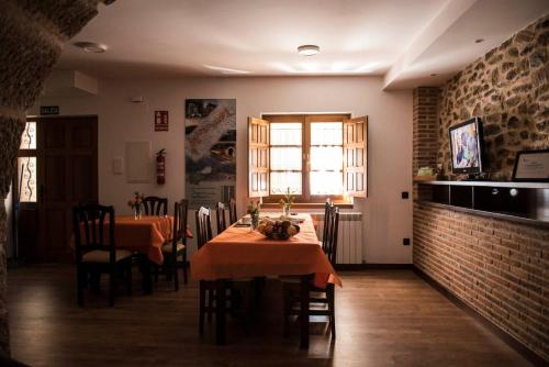 a dining room with a table and chairs and a brick wall at Dos Aguas Arribes in Fermoselle