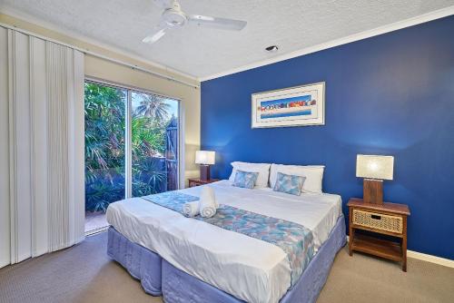 a blue bedroom with a large bed and a window at North Cove Waterfront Suites in Cairns
