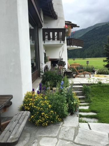 a porch of a house with a bench and flowers at Chesa Suot Ovas in Sils Maria