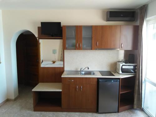 a small kitchen with wooden cabinets and a sink at Guest House D. Bogdanova in Obzor