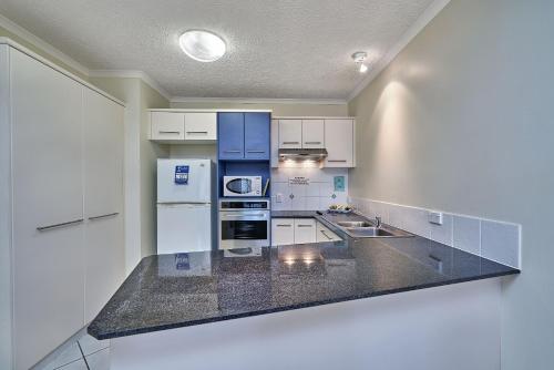 a kitchen with white cabinets and a black counter top at North Cove Waterfront Suites in Cairns