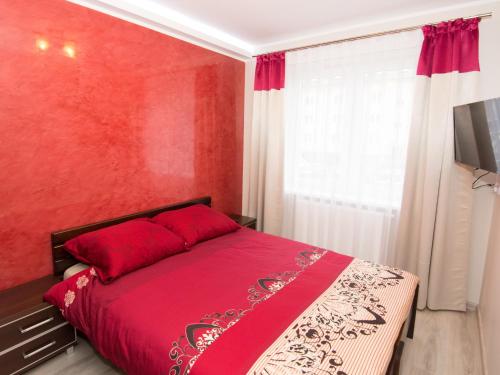 ein rotes Schlafzimmer mit einem Bett mit einer roten Wand in der Unterkunft Living Room New in Tarnów