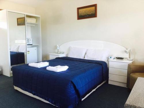 a bedroom with a blue bed with towels on it at Springsure Overlander Motel in Springsure