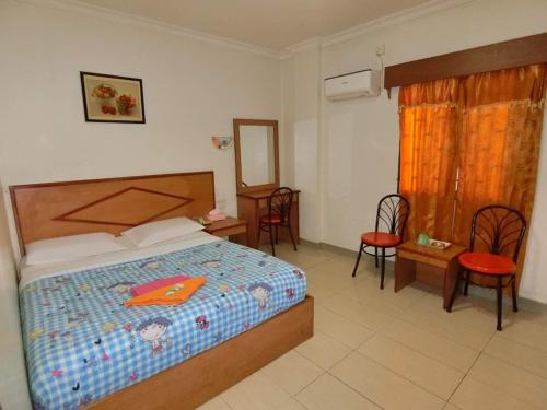 una camera con letto e sedie di HOTEL SUPER 888 a Tanjung Balai Karimun