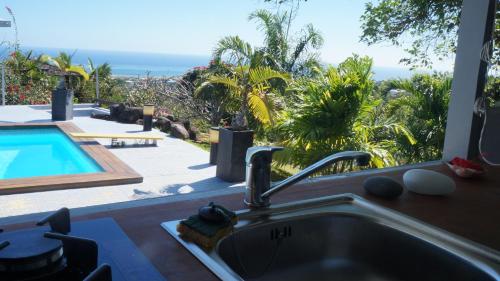 a kitchen sink with a view of a swimming pool at Bungalow Premium Tahiti in Punaauia
